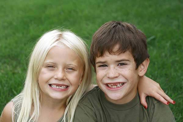 Boy and girl showing their missing teeth in the mouth